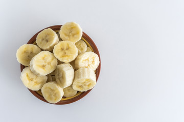 Bowl with banana slices on white background