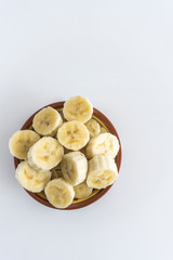 Bowl with banana slices on white background