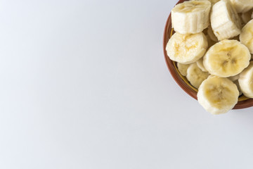Bowl with banana slices on white background