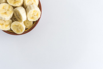 Bowl with banana slices on white background