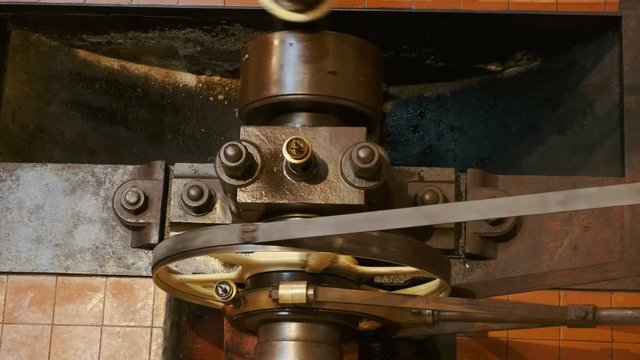 Top-down view of a flywheel of a single cylinder industrial steam engine in operation