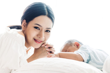 Portrait of happy smiling mother playing with baby on bed at home