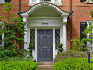 elegant front door with portico and shrubs