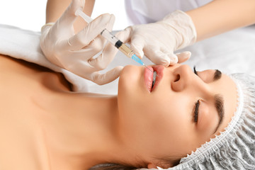 Naklejka premium Plastic lips surgery beauty concept young brunette woman face and doctor hand in glove with syringe