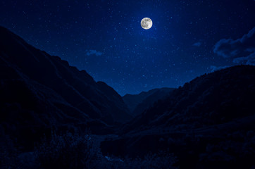 Fototapeta na wymiar Mountain Road through the forest on a full moon night. Scenic night landscape of dark blue sky with moon. Azerbaijan
