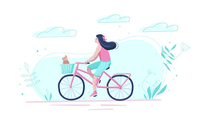 The cute girl goes by bicycle with a dog in a basket down the street.