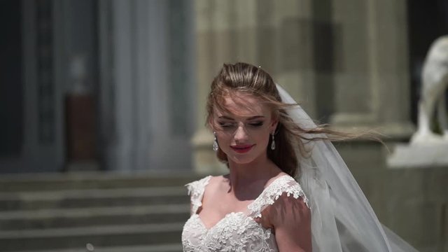 Young bride posing in a city. Waving veil at windy summer day. Slowmotion