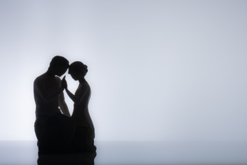 Couple Silhouette sitting down and holding hands in a display of love, passion or intimacy.
