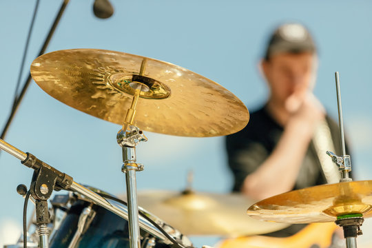 Close-up of a cymbal of a drums with musician out of focus in the background