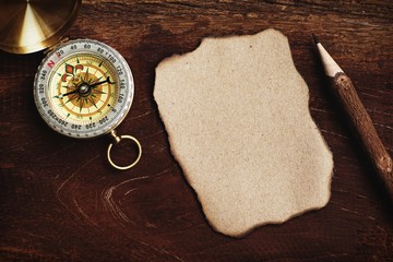 Compass, burnt brown paper and wooden pencil on crumples paper background, vintage tone, journey...