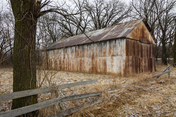 Old rusted metal building in open field.