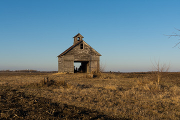 Old weathered wooden barn in open field on a Winter afternoon.  LaSalle County, Illinois, USA