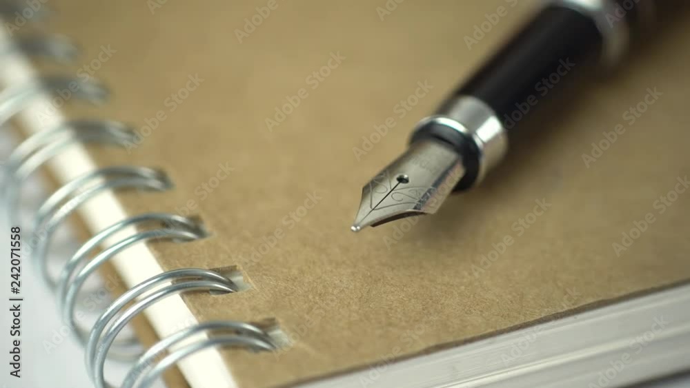 Poster expensive pen on notebook with a sliding camera move. 4k stock footage.