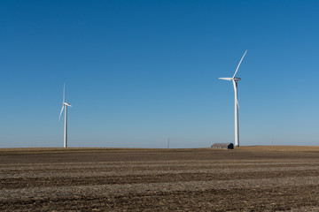 Old wooden barn and windmill in open farmland.