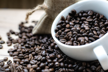 Coffee beans are placed in containers and spread on the background of wood grain.