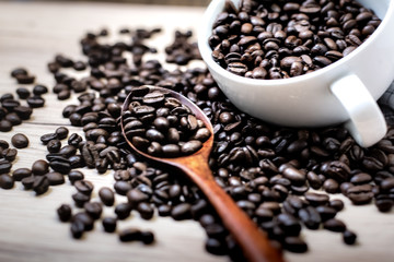 Coffee beans are placed in containers and spread on the background of wood grain.