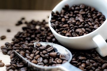 Coffee beans are placed in containers and spread on the background of wood grain.