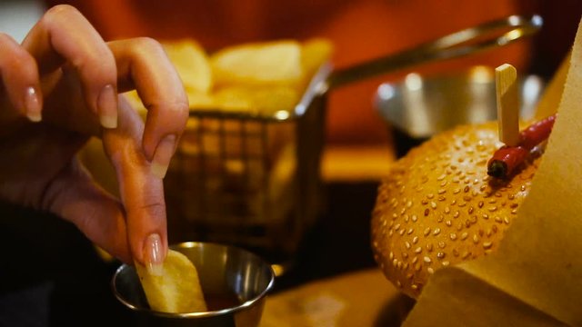 French fries. Hand dunks french fries in ketchup