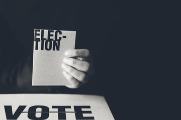 hand holding election card and vote box, democracy concept, black and white tone