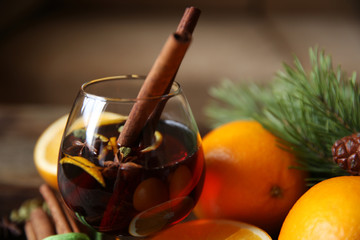 still life with mulled wine in a glass with two sticks of cinnamon and spices  with a fir-tree branch close-up. Christmas party.