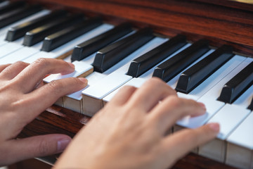 Obraz premium Closeup image of hands playing a vintage wooden grand piano