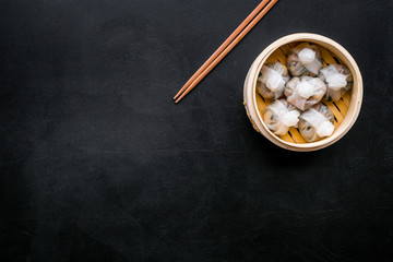 Chinese food set with dim sum, sticks on black background top view copy space