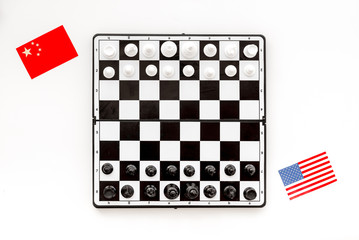 Chess competition concept. Chess board with figures near american and chinese flags on white background top view