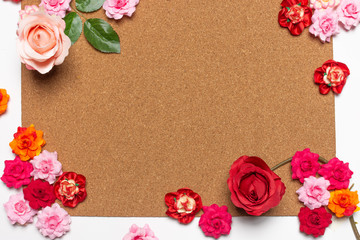 Frame made of rose flowers on cork board  background. Top view with copy space.