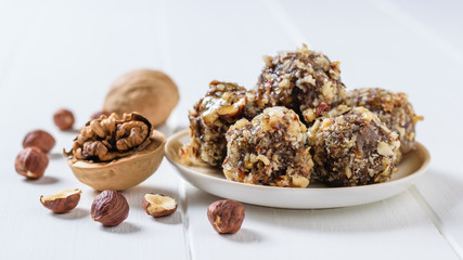 Homemade sweets made of nuts, dried fruits, chocolate and honey on a plate on a white table.