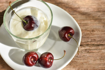 Fresh red cherries and plain yogurt served in white plate. Healthy eating.
