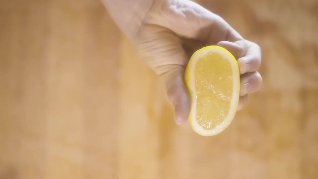 Close up slow motion shot of squeezing lemon with hands