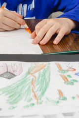 Boy coloring at table with color pencils.