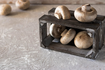 Raw champignons on a rustic wooden box