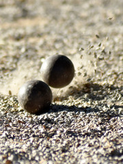 Fototapeta na wymiar Throwing one petanque ball against another ball until the small pebbles bounce along the impact.