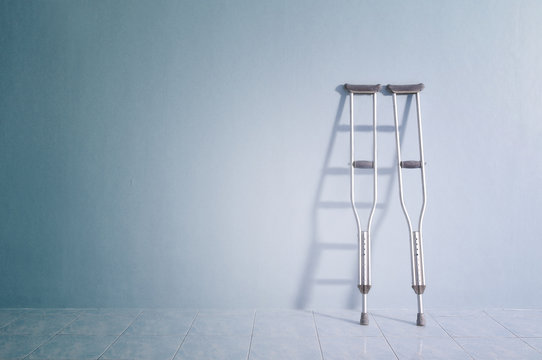 Success concept with crutches in the shadow of ladder.