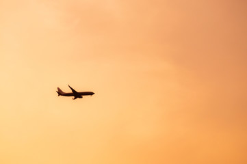 Fototapeta na wymiar Airplane flying in warm tone sunset sky on cloudy day