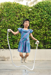 Portrait of asian little girl jumping handmade rope among swing in the park.selective focus.