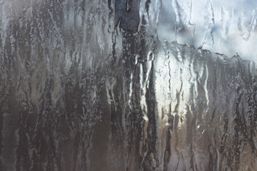 Fototapeta premium Frozen ice on glass window. Gray background