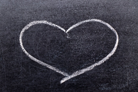 White chalk hand drawing in heart shape on black board background
