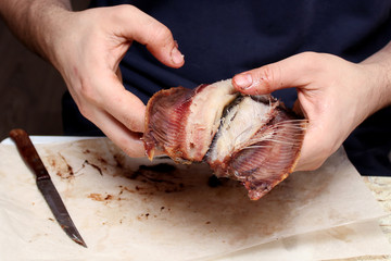 Hands of a man holding salted fish with protruding bones and cooking it