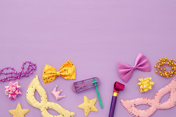 Purim celebration concept (jewish carnival holiday) over pink wooden background. Top view.