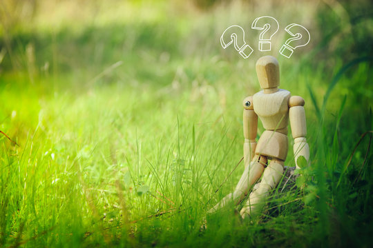 concept photo of wooden dummy sitting outdoors thinking. New idea concept or choosing the right solution.