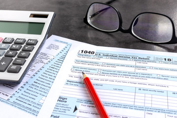United States federal income tax return IRS 1040 documents, with pencil, calculator and eyeglasses