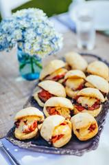 burger sliders sitting on table near flowers ready to be eaten
