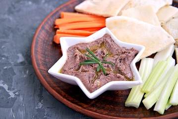 Red bean dip with baked garlic, thyme and olive oil in a star bowl. Served with chopped raw carrots, celery and pita pieces.
