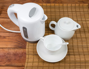 Plastic electric kettle, teapot and cup on old wooden table