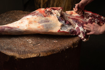 A butcher with cleaver and raw meat on wooden cutting board