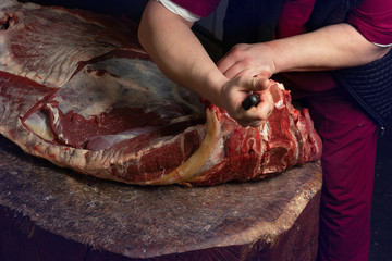 a butcher cuts a large carcass of meat
