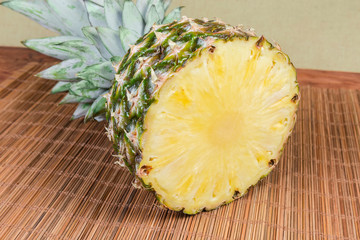 Half of fresh pineapple on bamboo table mat close-up