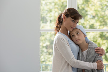 Caring mother hugging sick daughter with cancer during chemotherapy